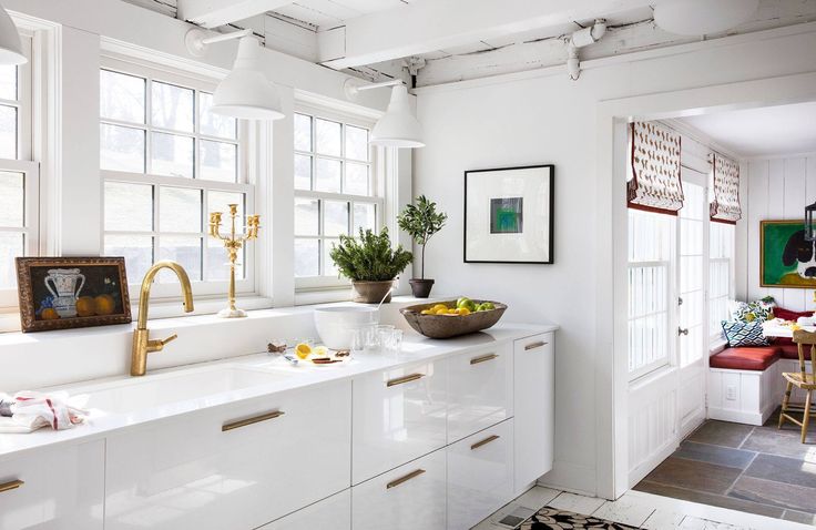 a kitchen filled with lots of white cabinets and counter top space next to a window