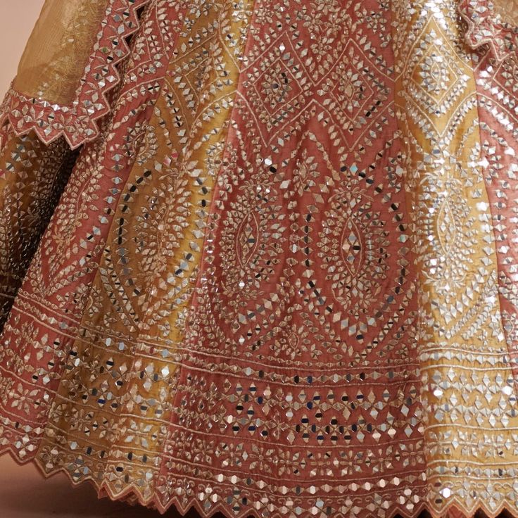 Step into effortless elegance with the Rust and Mustard Silk Lehenga, a perfect style for Mehendi celebration. This opulent lehenga radiates tradition featuring meticulous gota and mirrorwork that capture the light with every movement. The classic rust blouse is adorned with exquisite embroidery, complementing the vibrant mustard gold dupatta that cascades effortlessly, adding a touch of grace to your silhouette. Perfectly blending craftsmanship and style, this embroidered Lehenga is more than j Elegant Gota Work Choli For Festive Season, Elegant Navratri Choli With Gota Work, Elegant Gota Work Choli For Navratri, Elegant Choli With Gota Work For Diwali, Elegant Gota Work Choli For Diwali, Elegant Semi-stitched Gota Work Choli, Elegant Kundan Lehenga With Gota Work, Elegant Semi-stitched Choli With Gota Work, Festive Mirror Work Salwar Kameez For Reception