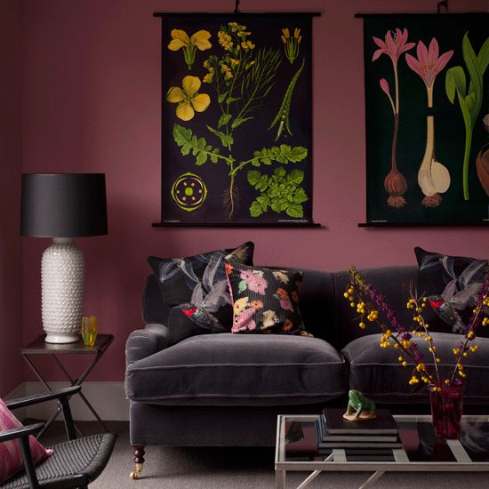 a living room with purple walls and paintings on the wall above it's couch