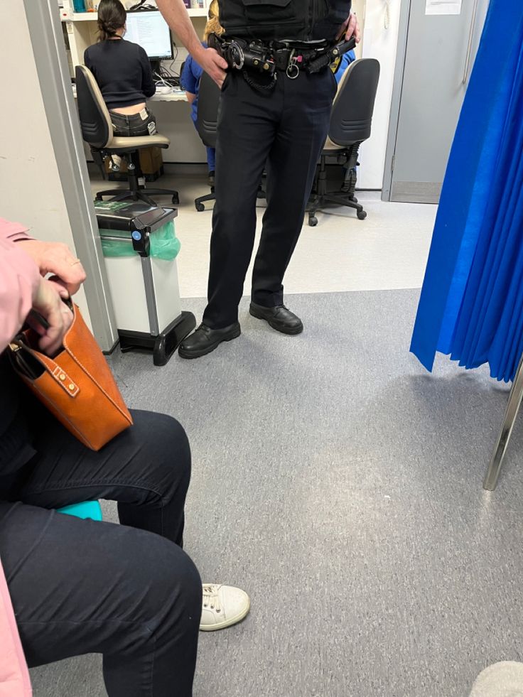 a police officer standing next to a woman in a pink shirt and black pants with her hand on her purse