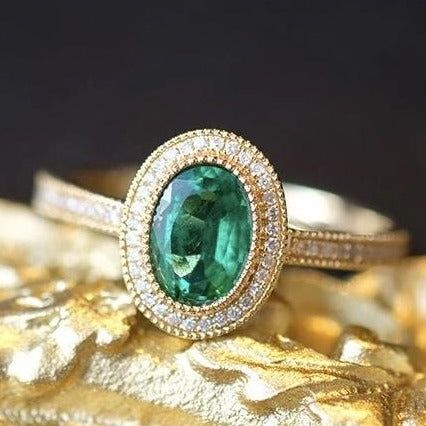 - Sophisticated Oval Engagement Ring Vintage - Superior Quality and Craftsmanship - Nature Inspired Green Ring - Vivid Green Natural Emerald - Ethically Sourced Gemstones - Conflict Free Diamonds - Made in the USA Have you ever seen something more beautiful than emerald ring in yellow gold surrounded by a sparkly diamo Emerald Ring With Diamonds, Emerald Ring Engagement, Emerald Engagement Ring Vintage, Emerald Green Ring, Vintage Oval Engagement Rings, Blue Green Sapphire Ring, Vintage Emerald Engagement Ring, Montana Sapphire Engagement, Montana Sapphire Engagement Ring