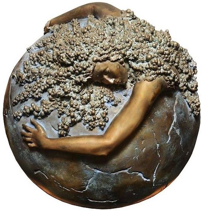 a bronze sculpture of a woman sleeping on top of a stone ball with trees growing out of it