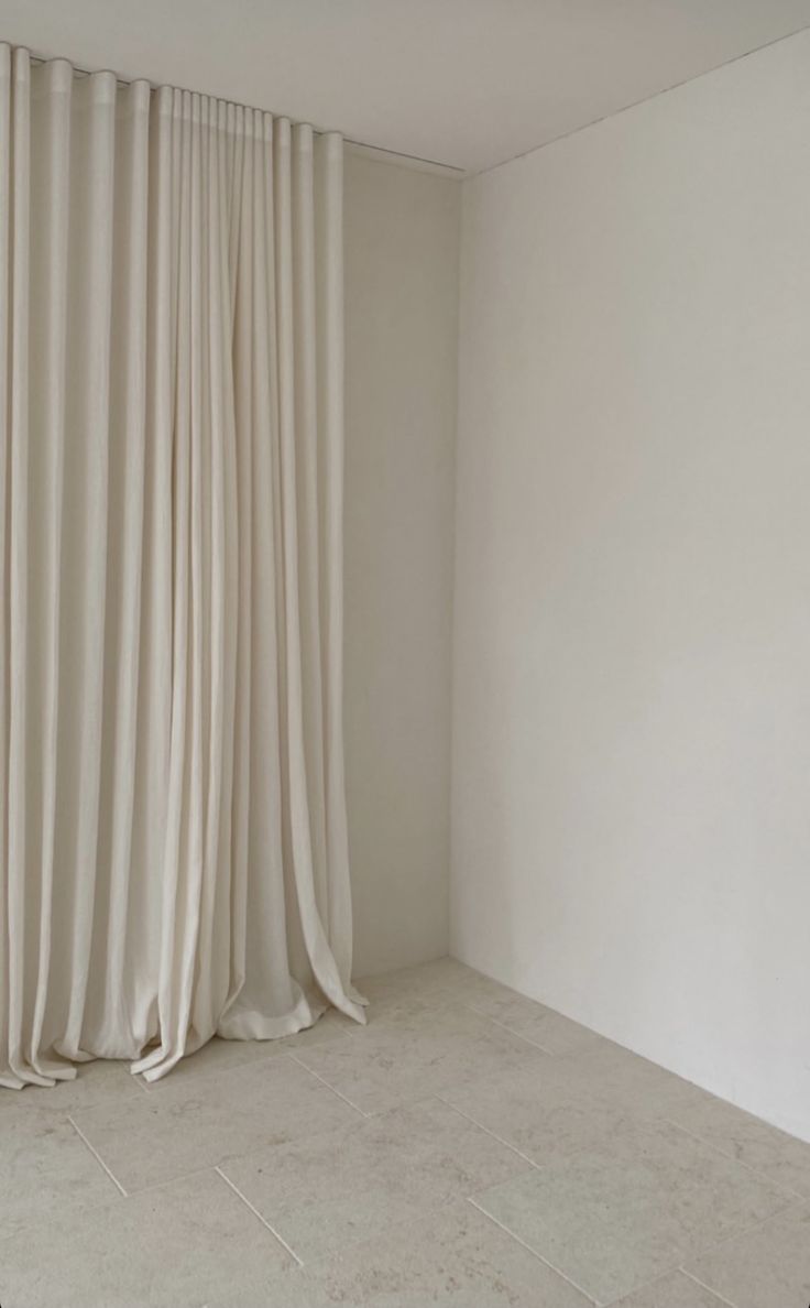 an empty room with white walls and curtains