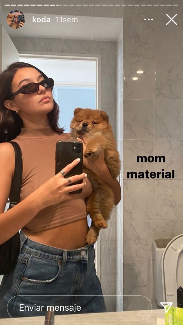 a woman taking a selfie in the mirror with her dog on her lap while holding a cell phone