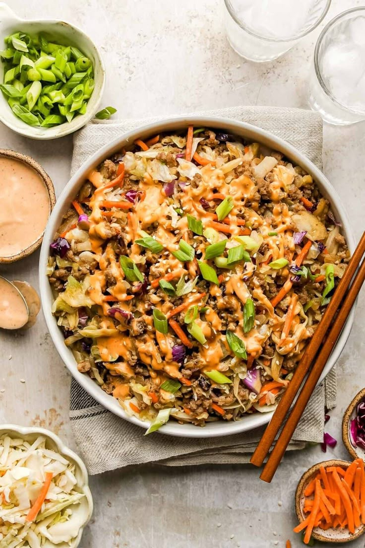 a bowl filled with rice and vegetables next to chopsticks on a napkin near other bowls