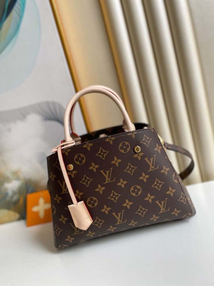 Named for an elegant avenue in Paris, the Montaigne BB handbag is both chic and impeccably functional. Made from Monogram canvas, it features a smart interior with a host of compartments and pockets to keep belongings secure. This compact model is ideal for office to off-duty use, with its long, cross-body strap for hands-free wear. Detailed Features 29 x 20 x 13 cm (Length x height x width ) Monogram canvas Natural cowhide-leather trim Burgundy microfiber lining Gold-color hardware Hook to secure belongings Key bell Central zipped compartment with padlock 2 wide compartments Double smartphone pocket Flat pocket 4 protective metal bottom studs Strap: Removable, not adjustable Strap Drop: 55.0 cm Handle: Double The reference is either made in France, Spain, Italy or in the US. Lv Montaigne, Louis Vuitton Montaigne, Bb Monogram, Mm Monogram, Business Bag, Vuitton Bag, Monogram Canvas, Wallet Case, Cowhide Leather