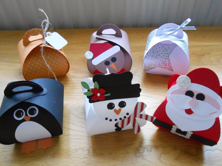 four small christmas gift bags sitting on top of a wooden table next to each other