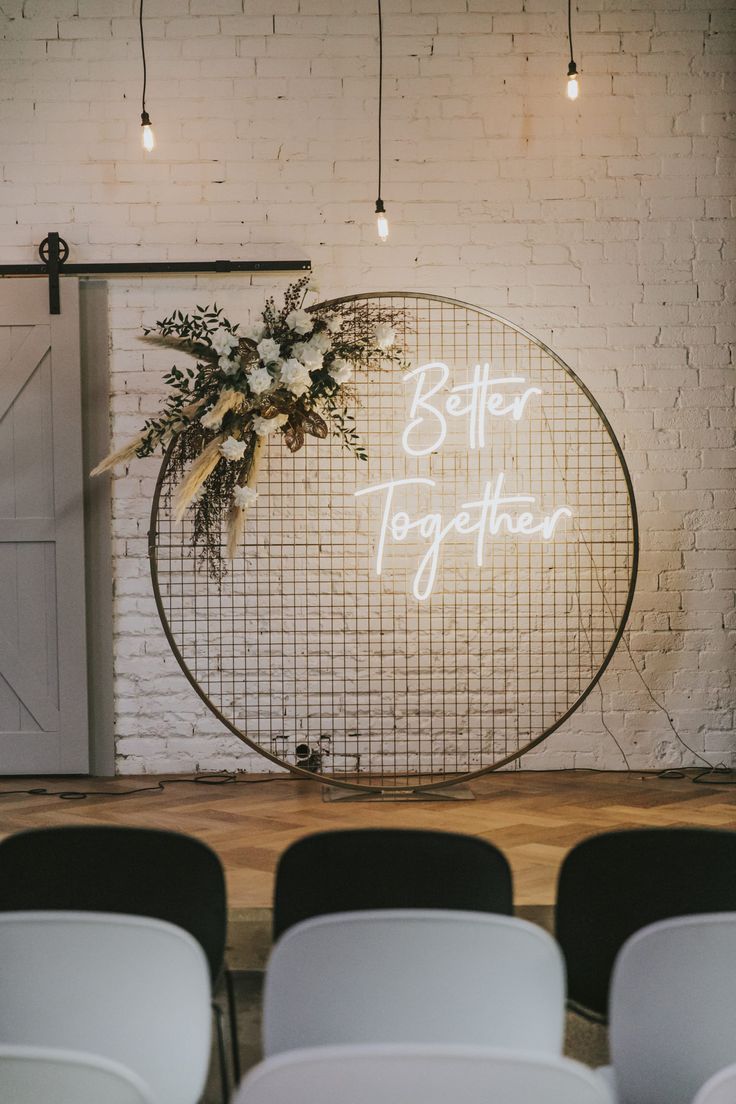 a sign that says better together in front of a white brick wall with chairs around it