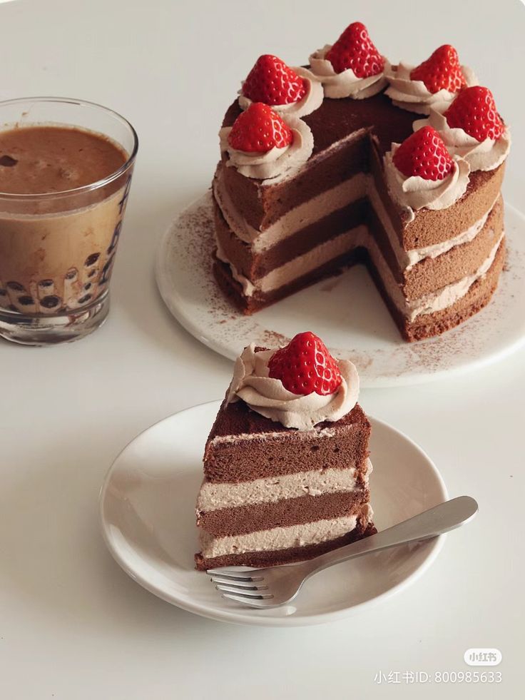 two slices of chocolate cake with strawberries on top and a cup of coffee in the background