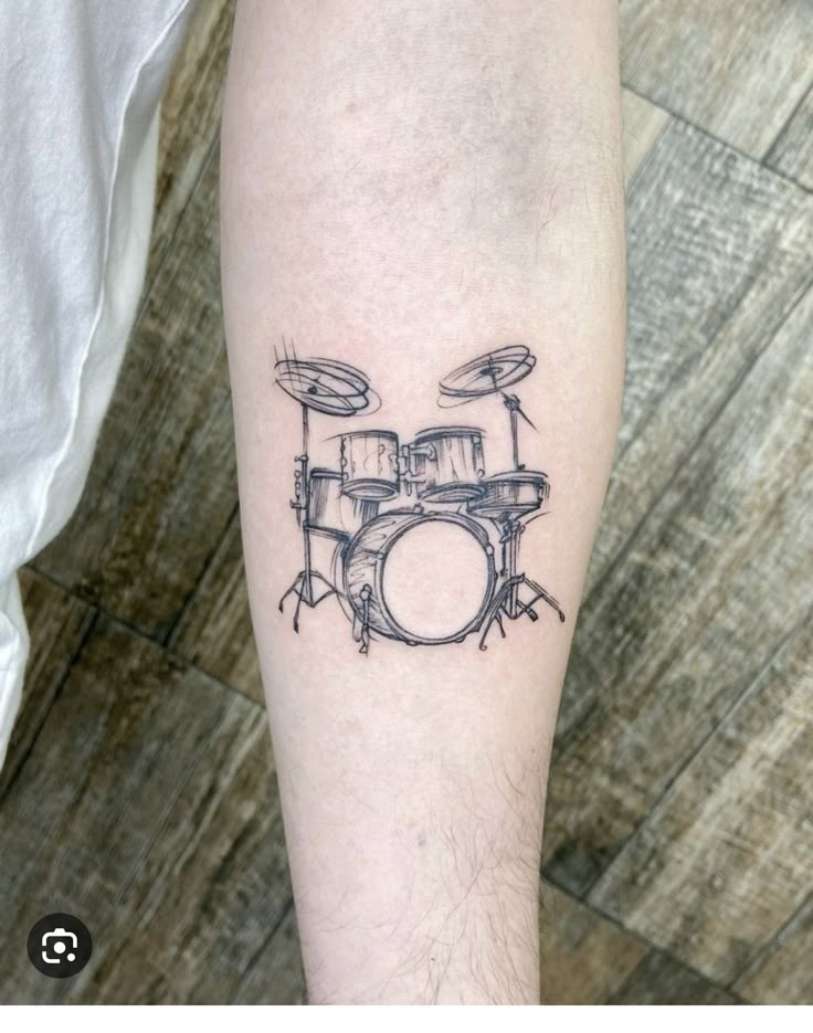 a black and white photo of a drummer's drum set tattoo on the leg