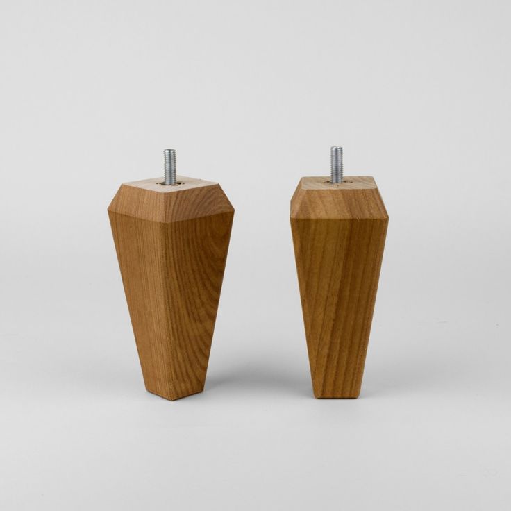 two wooden pedestals with nails sticking out of them on a plain surface, one is made from wood and the other is made of metal