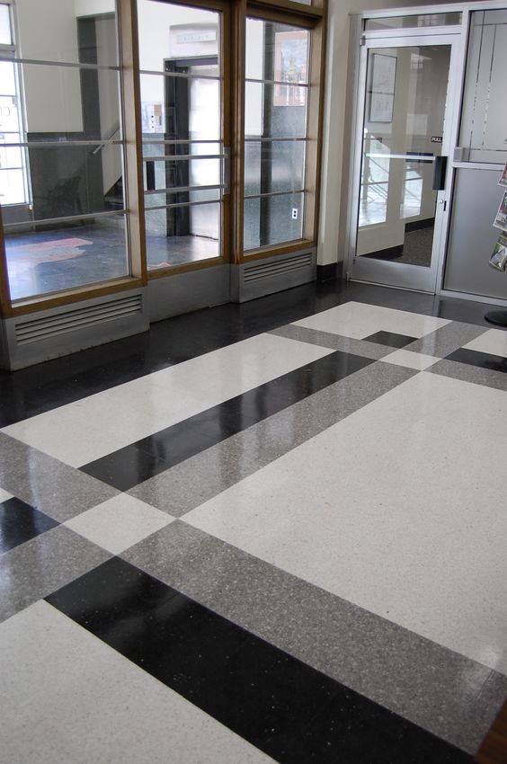 an empty room with black and white checkered flooring in front of glass doors