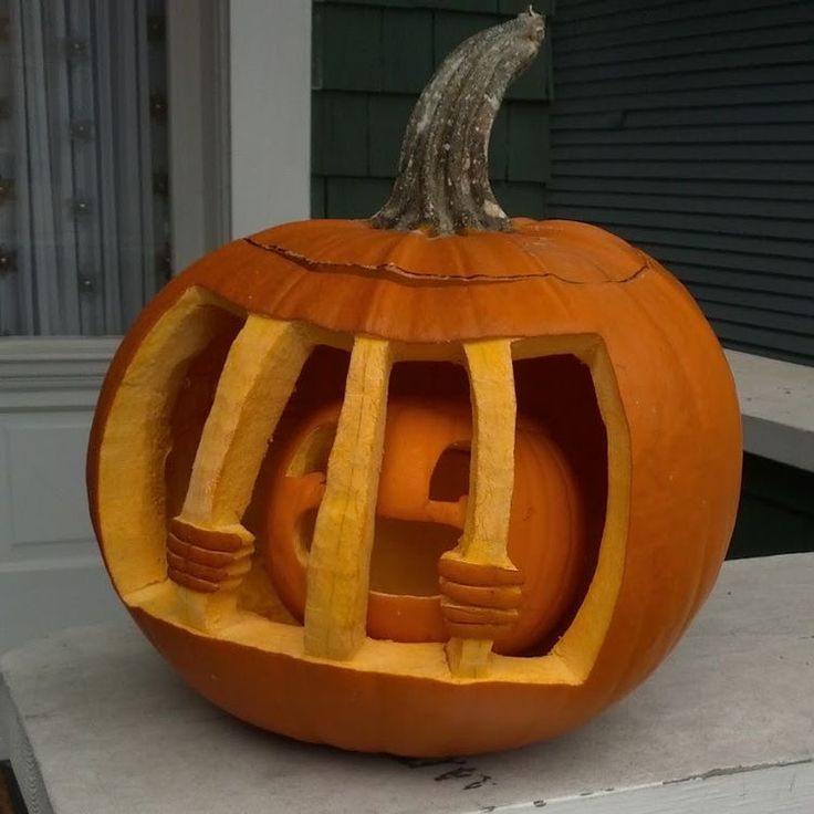 a carved pumpkin sitting on top of a cement slab next to a building with a rat in it