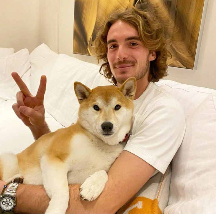 a man sitting on top of a bed holding a brown and white dog in his arms