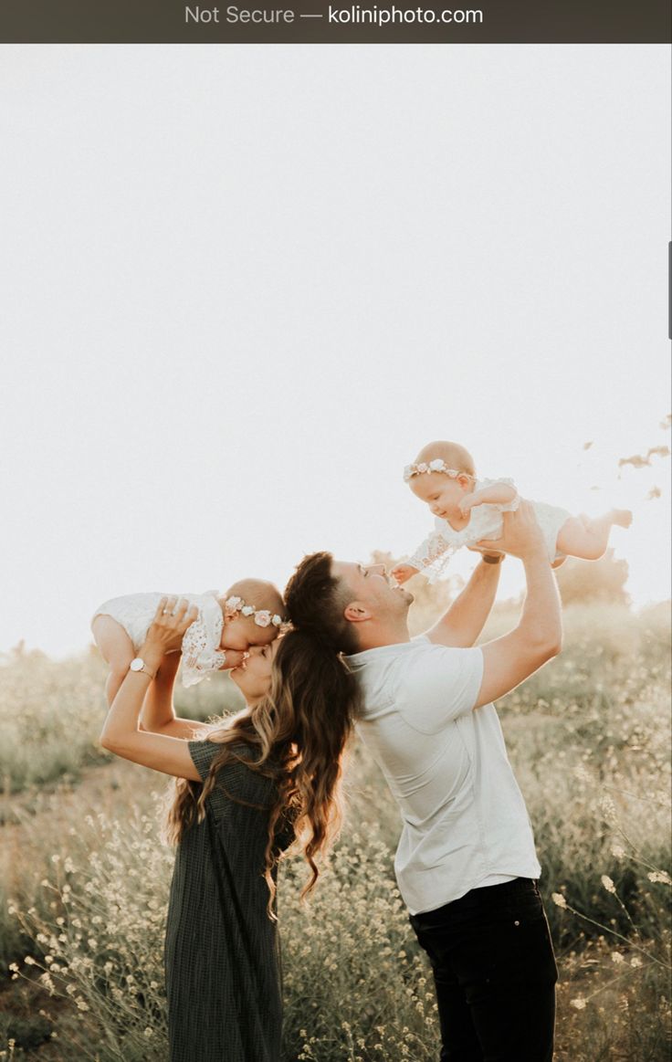 a mother and her two babies playing in a field with the sun shining on them