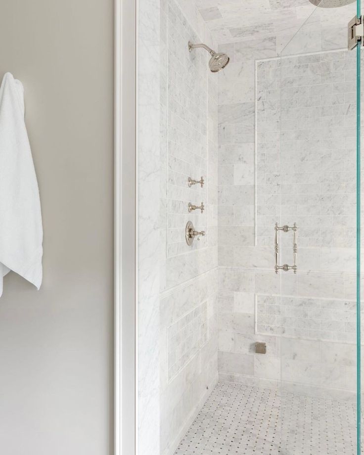 a walk in shower sitting next to a white towel hanging on the wall above it