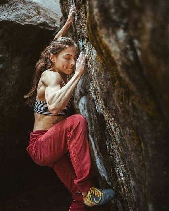 a woman climbing up the side of a rock