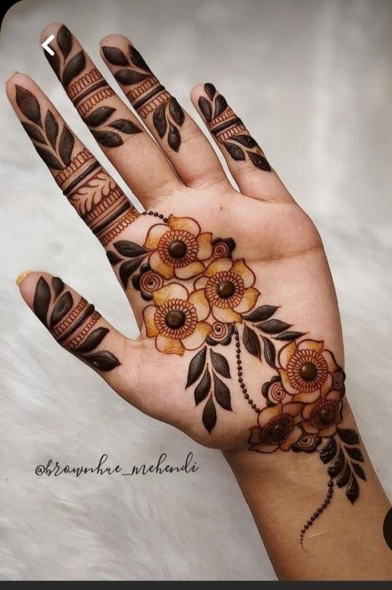 a woman's hand with hennap and flowers painted on the top of it