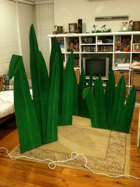 a living room filled with furniture covered in fake grass and green plants on the floor