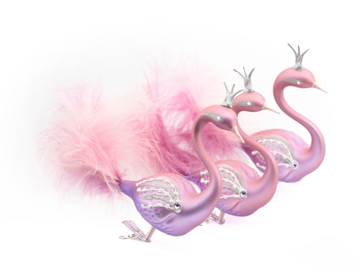 three pink flamingos with feathers on them are sitting in front of a white background