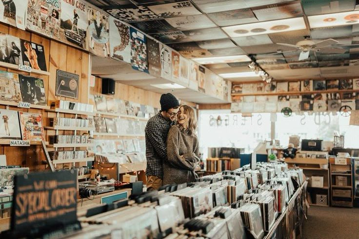 a man and woman standing next to each other in a room full of recordshelves