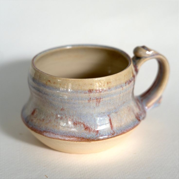 a close up of a small cup on a table with a white surface in the background