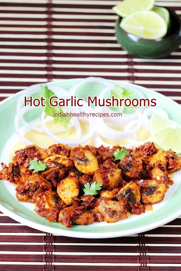 hot garlic mushrooms served on a plate with lemon wedges and garnishes