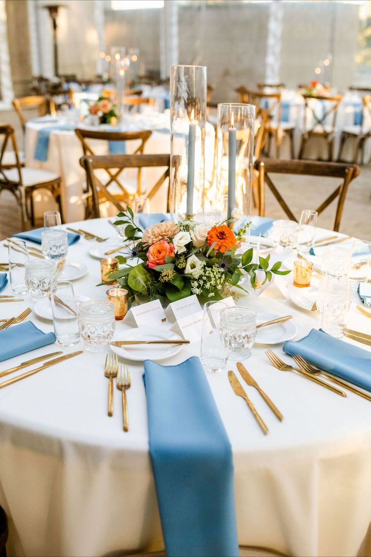 the table is set with blue and white linens, silverware, and flowers