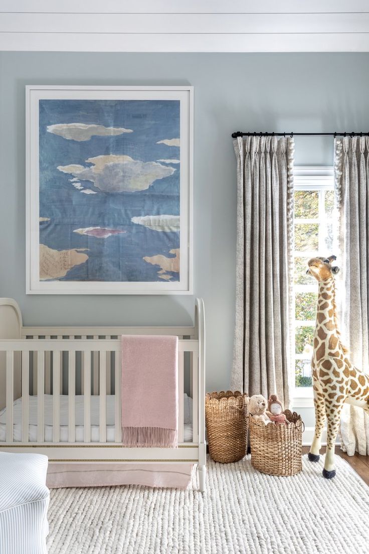 a giraffe standing next to a baby crib in a room with blue walls