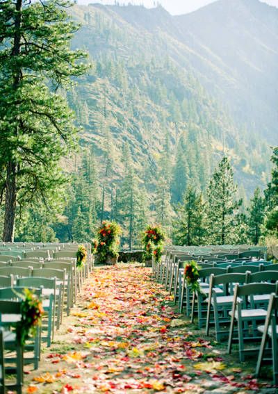 rows of chairs with flowers and greenery on the ground at a wedding ceremony in the mountains