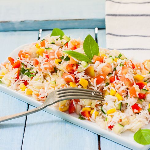 a white plate topped with rice and veggies on top of a blue table