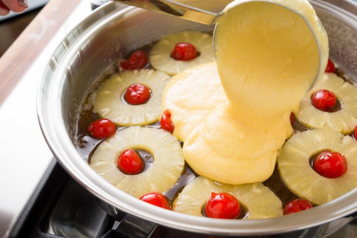 pineapples and cherries are being cooked in a pot with a ladle