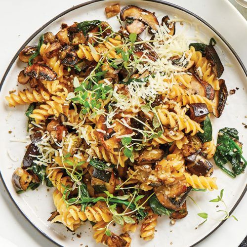 pasta with mushrooms, spinach and parmesan cheese on a white platter