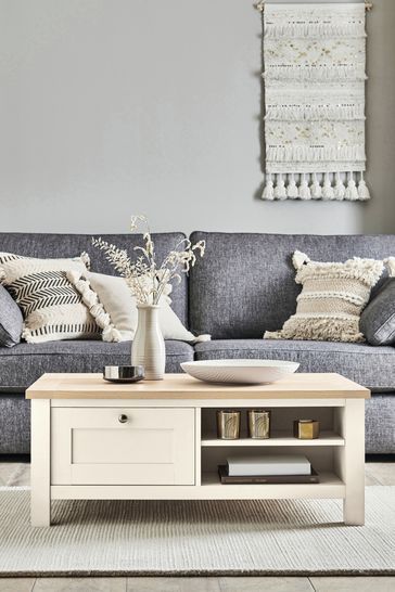 a living room with grey couches and pillows on the floor, white coffee table