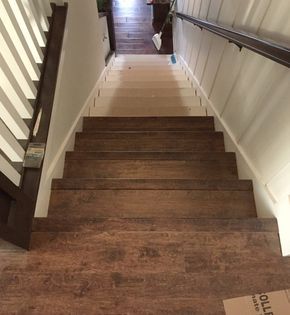 stairs leading up to the second floor with white walls and brown wood treading on each side