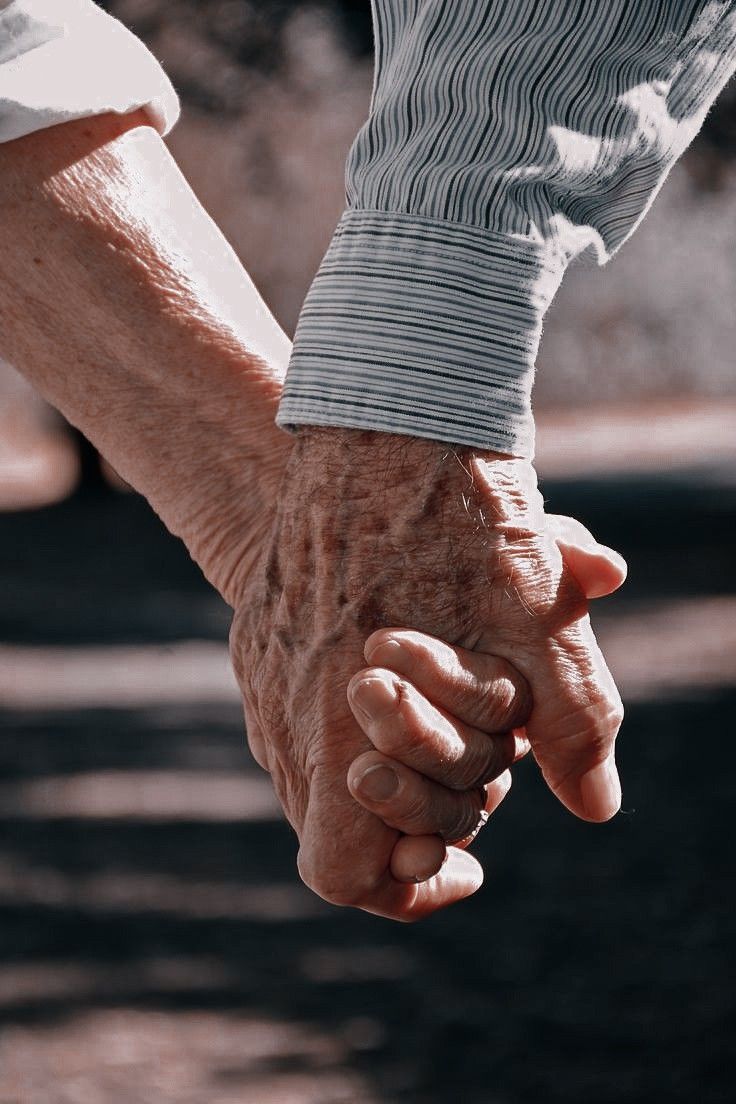 an older person holding the hand of a younger person who is holding their hands together