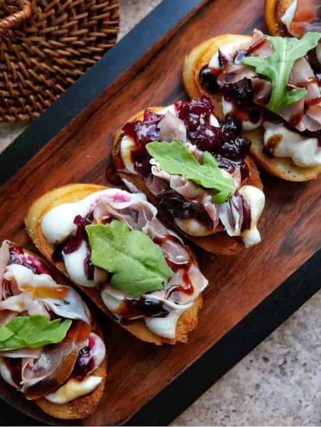 small sandwiches with meat, cheese and greens on a wooden tray