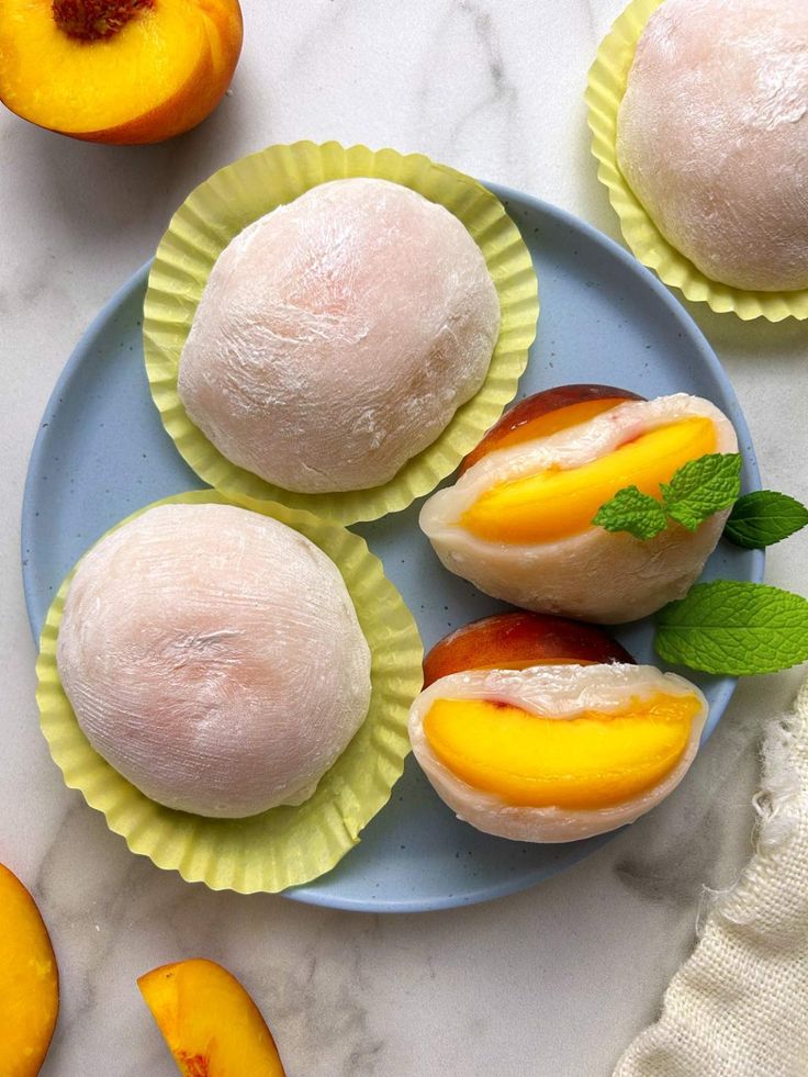 three peaches and two pieces of bread on a blue plate with mint garnish