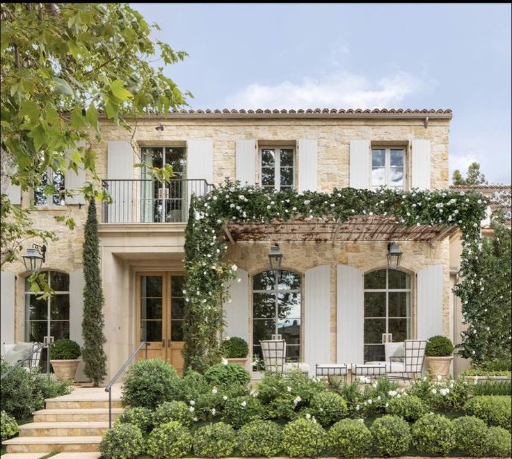 a house with white shutters and ivy growing on the front door, steps leading up to it