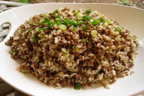 a white plate topped with brown rice and green onions