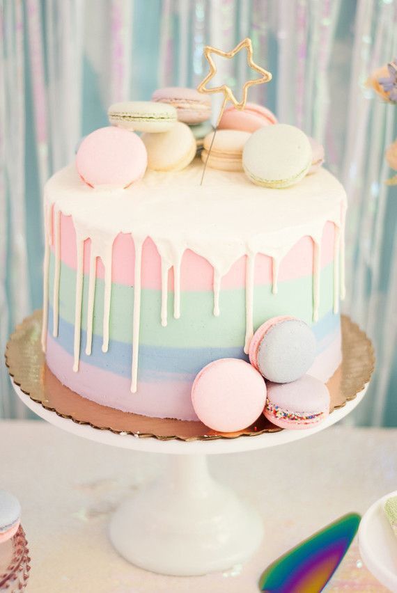 there is a cake with icing on the top and macaroons around it