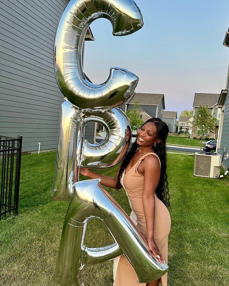 a woman standing in front of a giant number balloon