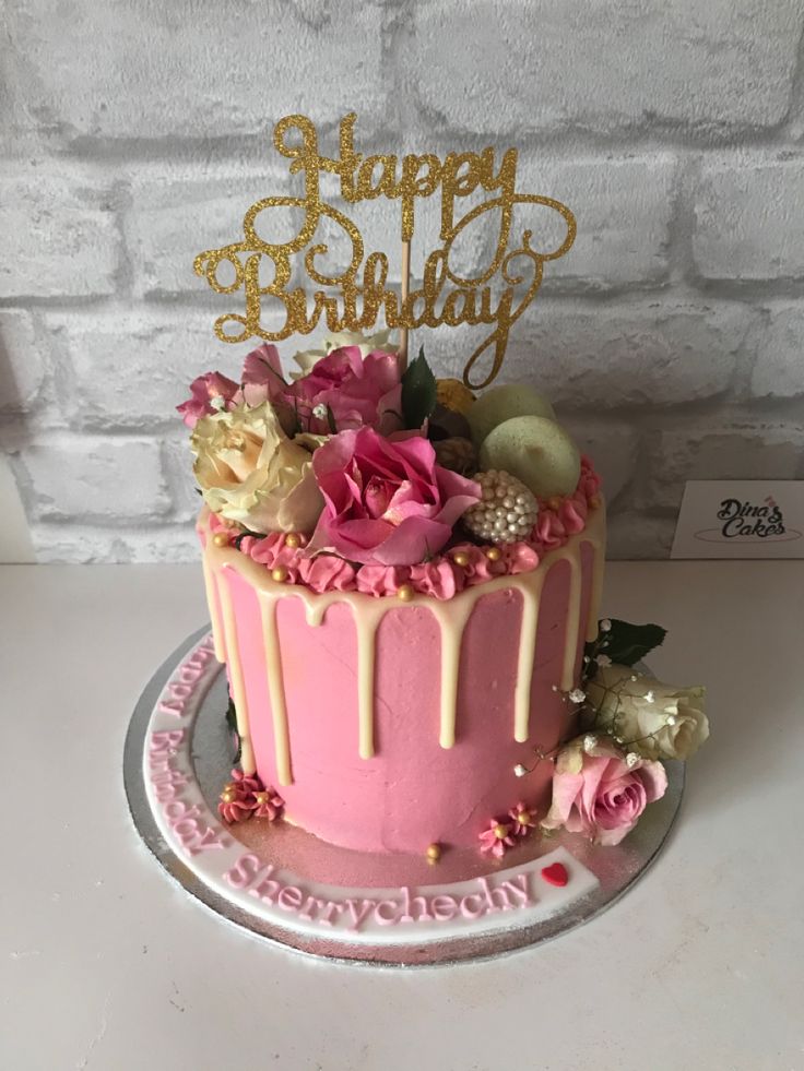 a birthday cake with pink frosting and flowers on the top that says happy birthday