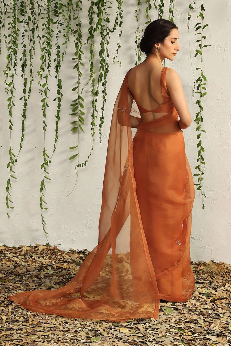 Editor's Note Crafted in feather touch pure organza fabric in a rich spice orange colour and intricate nakshi hand embridery inspired by the leaf motif, this saree looks like a dream. A deep neck chanderi sleeveless blouse adds to the glamorous feel. Fabric: Blouse: chanderi, sari: organza Color: Orange Component: Sari and blouse Occasion: Festive Note: Product colour may slightly vary due to photographic lighting sources Care: Dry clean only About the Designer A brand that seeks inspiration in Luxury Orange Embroidered Saree, Luxury Unstitched Orange Saree, Luxury Orange Pre-draped Saree For Diwali, Luxury Embroidered Orange Saree, Luxury Orange Saree With Unstitched Blouse, Luxury Orange Saree For Diwali, Luxury Orange Anarkali Saree, Saree Poses Photoshoot Ideas, Wedding Guest Saree