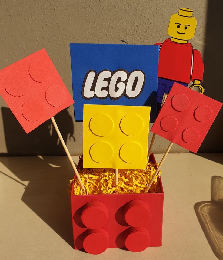 a lego cake made to look like it has been placed in a box with sticks