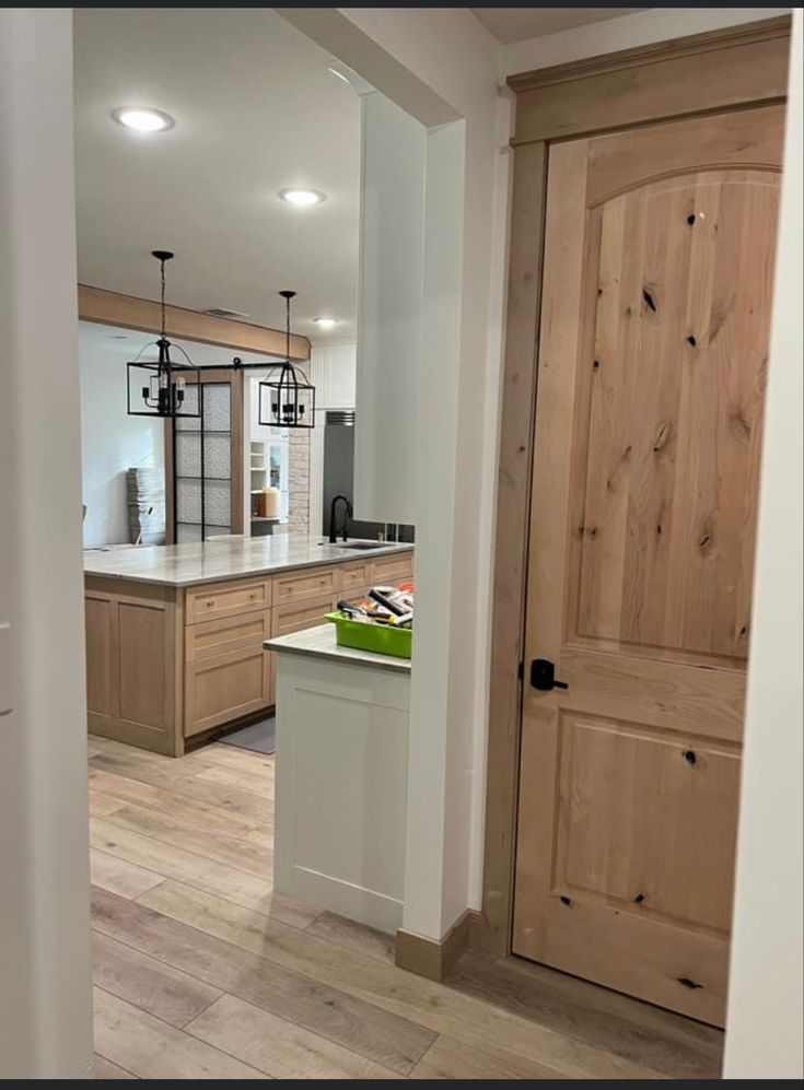 an open kitchen with wooden cabinets and white counter tops, along with hardwood flooring