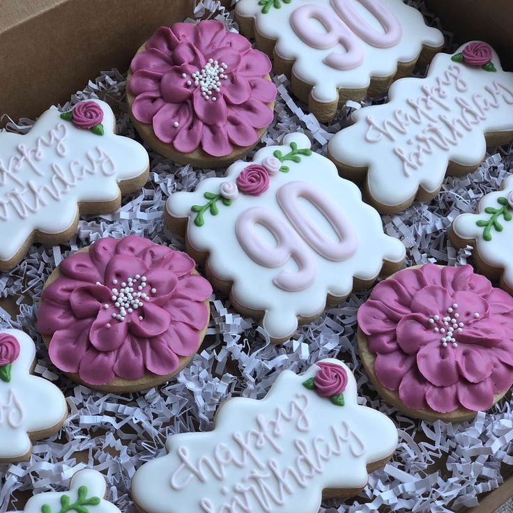 decorated cookies in a box with pink and white frosting on the top one is for an 80th birthday