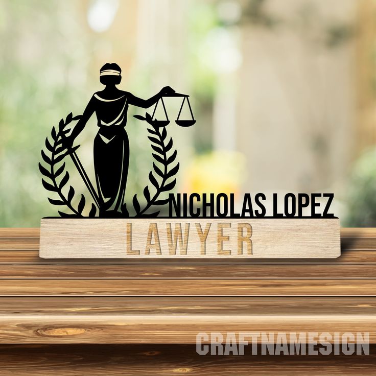 a wooden table topped with a sign that says nicholas lopez lawyer and an image of a lady justice figure