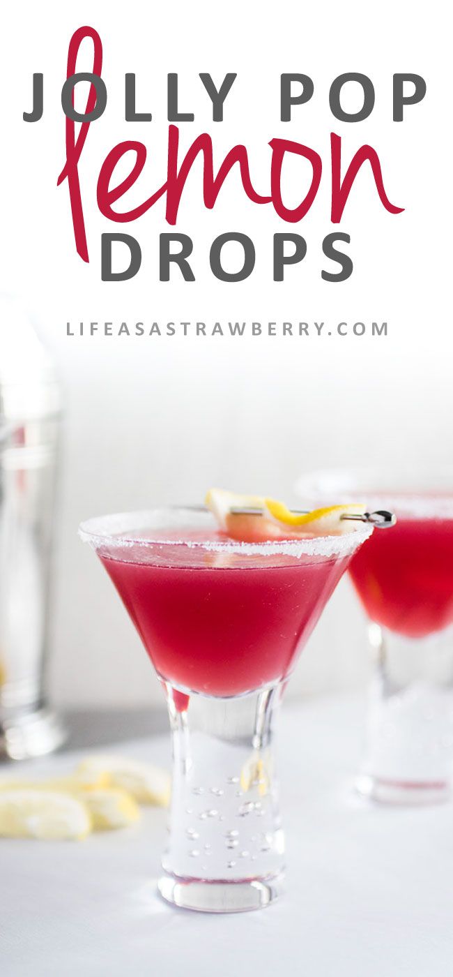 two glasses filled with red liquid sitting on top of a table next to lemon wedges