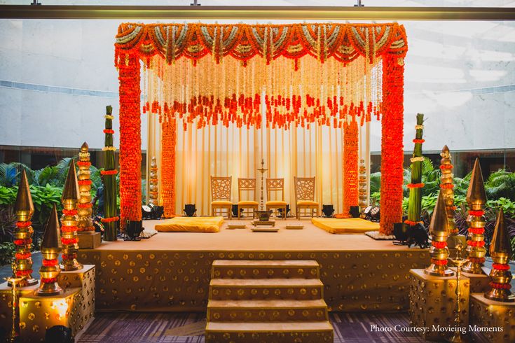 a decorated stage set up for a wedding ceremony with candles on the floor and decorations